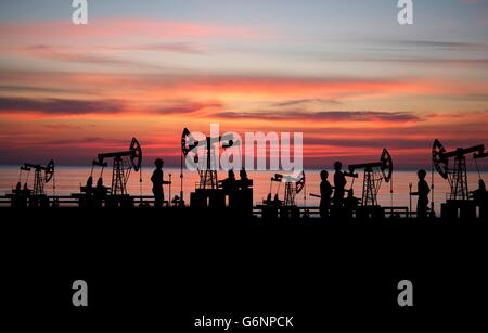 Deux homme sur oilfield avec pompe sur fond coucher de soleil Banque D'Images