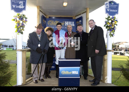 Les liens gagnants de Cloudy aussi, y compris jockey Jonathan Angleterre (troisième à gauche), après la victoire dans le William Hill Rowland Meyrick handicap Chase Banque D'Images