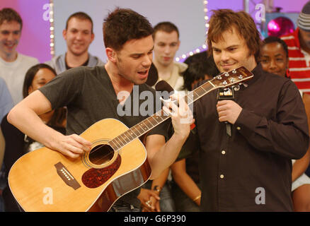 L'animateur Dave Berry (L) apprend à faire du rock avec l'acteur Jack Black lors de son apparition sur le site TRL UK de MTV aux studios MTV de Camden, dans le nord de Londres. Banque D'Images