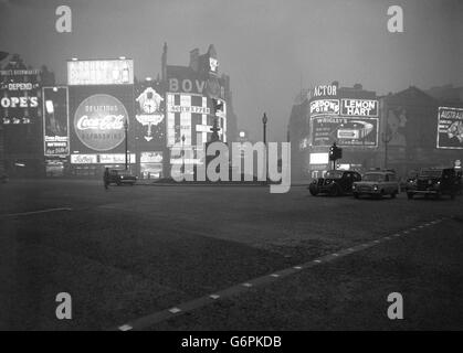 Le matin ressemble à minuit à Piccadilly Circus à 9:30. Comme le pire brouillard de l'hiver qui entoure encore Londres, les panneaux électriques s'allument à travers le feu et les véhicules utilisent leurs feux. Banque D'Images