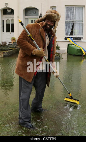 Kye Gbangbola élimine les eaux d'inondation de l'extérieur de sa maison près du pont Chertsey à Chertsey, Surrey, car des communautés le long de la Tamise dans tout le Surrey, le Berkshire et l'Oxfordshire ont été prévenus qu'elles risquent d'être inondées. Banque D'Images