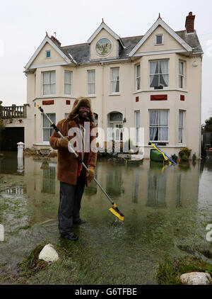 Kye Gbangbola élimine les eaux d'inondation de l'extérieur de sa maison près du pont Chertsey à Chertsey, Surrey, car des communautés le long de la Tamise dans tout le Surrey, le Berkshire et l'Oxfordshire ont été prévenus qu'elles risquent d'être inondées. Banque D'Images