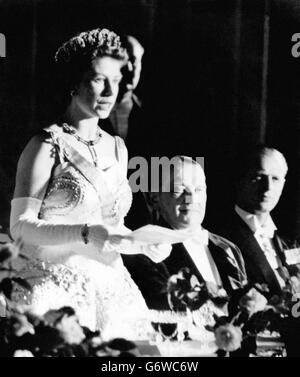 La reine Elizabeth II, parlant en français, répond aux toasts du président français René Coty (au centre) lors d'un dîner tenu à l'Elysée, à Paris, le premier jour de la visite d'État de quatre jours.Le duc d'Édimbourg écoute l'extrême droite. Banque D'Images