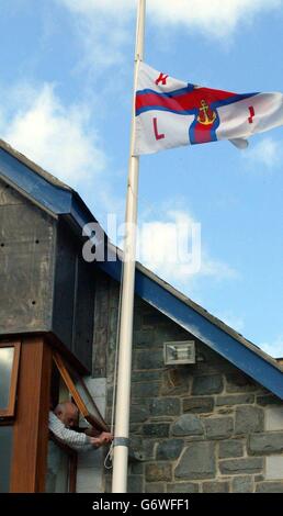 Le drapeau de la RNLI (Royal National Lifeboat institution) est abaissé à Barmouth, au nord-ouest du pays de Galles, après la découverte d'un corps. Deux membres de l'équipage du bateau de sauvetage - qui sont aussi le maître du port et le maître adjoint du port - ont été vus pour la dernière fois lundi matin, lorsqu'ils ont pris le départ pour déposer un amarrage. Après une recherche à grande échelle par des bateaux de sauvetage, des patrouilles de recherche des garde-côtes, des équipes de sauvetage en montagne, des policiers et des hélicoptères de la RAF, on a demandé aux familles des hommes de se préparer au pire. Banque D'Images