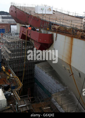 Workman travaille près de la rampe de décollage sur le pont alors que les travaux se poursuivent sur le porteur d'aéronefs HMS Queen Elizabeth à Rosyth Docks. Banque D'Images