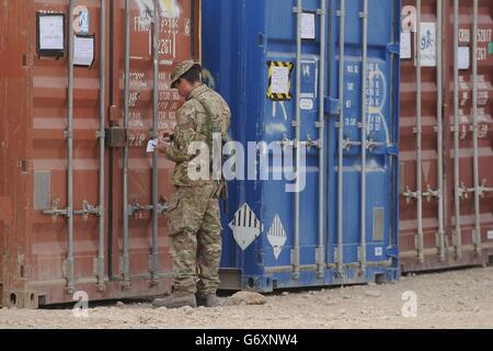 25/02/14 UN soldat vérifie les conteneurs ISO stockant l'équipement du camp avant d'être transporté hors de MOB Price dans la province de Helmand avant que les dernières troupes britanniques quittent le camp. Banque D'Images
