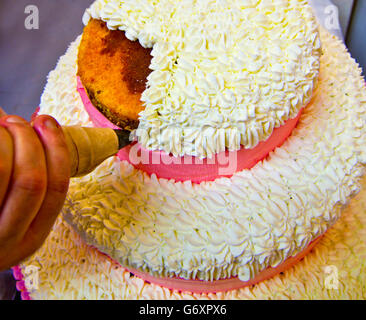 Du vrai chef pâtissier travaillant dans la décoration de la crème sur un gâteau pour un mariage Banque D'Images