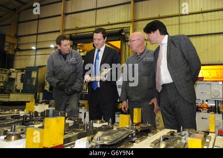 Le chancelier George Osborne s'efforce de travailler avec les chargehaines Matt Williams (à gauche) et Paul wicket (à droite) en tant que député conservateur de Halesowen et Rowley Regis James Morris (à droite) lors d'une visite à Cube Precision Engineering à Rowley Regis, West Midlands. Banque D'Images