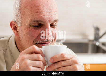 Close up sur seul beau bearded man avec les yeux fermés et heureuse expression sirotant du café de little white tea cup Banque D'Images