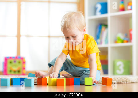 Bambin enfant jouant avec des blocs de jouets. Enfant jouant avec des jouets en bois à la maternelle ou garderie. Dans les jardins d'enfant. Banque D'Images