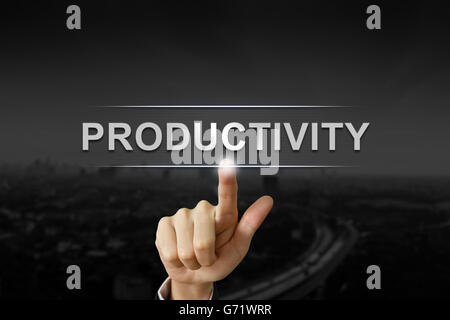 La main d'affaires en cliquant sur le bouton de la productivité sur l'arrière-plan flou noir Banque D'Images