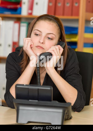 Ennuyer female office worker faisant un appel téléphonique Banque D'Images