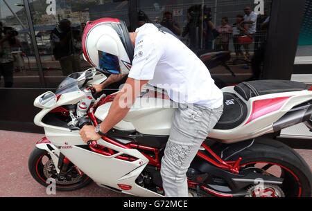 Lewis Hamilton, en Grande-Bretagne, arrive à bord d'un vélo à moteur dans le paddock du circuit de Monaco, Monte Carlo. Banque D'Images