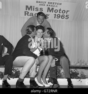 Jackie Peterson, de Saltdean, Brighton, détient le trophée après avoir été élue « course automobile 1965 » à Brands Hatch, Kent. Elle est félicitée des baisers des pilotes de course (l-r) Graham Hill, Jim Clark et Jack Brabham. Banque D'Images