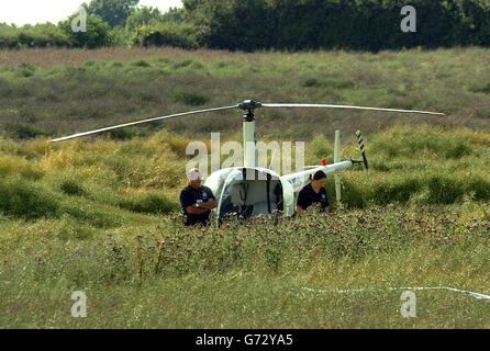 La police garde la garde à bord d'un hélicoptère qui a été forcé d'atterrir après une collision avec un avion microléger au-dessus de Welham Green, près de Hatfield dans le Hertfordshire. Deux personnes sont mortes dans l'accident. Banque D'Images