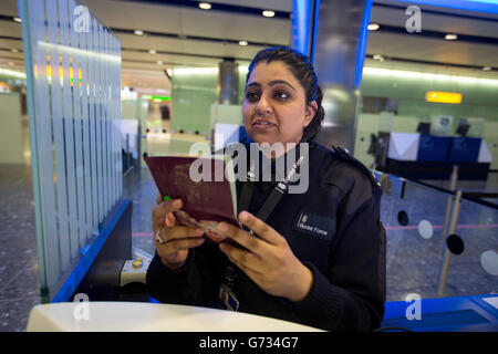 Un agent de la Force frontalière vérifie les passeports des passagers à l'arrivée dans le terminal 2, le terminal Queen, à l'aéroport de Heathrow, le premier jour d'opération. Banque D'Images