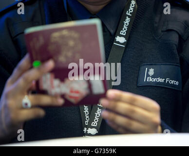 Un agent de la Force frontalière vérifie les passeports des passagers à l'arrivée dans le terminal 2 du terminal Queen de l'aéroport de Heathrow, qui a ouvert pour la première fois au public. Banque D'Images