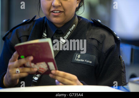 Un agent de la Force frontalière vérifie les passeports des passagers à l'arrivée dans le terminal 2 du terminal Queen de l'aéroport de Heathrow, qui a ouvert pour la première fois au public. Banque D'Images