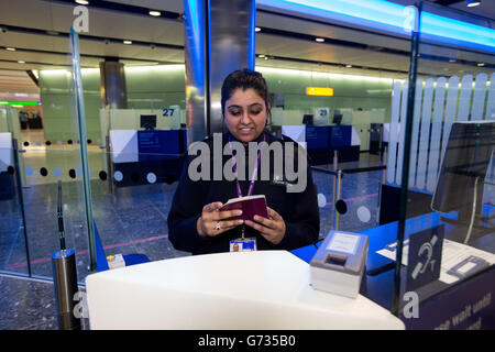 Un agent de la Force frontalière vérifie les passeports des passagers à l'arrivée dans le terminal 2 du terminal Queen de l'aéroport de Heathrow, qui a ouvert pour la première fois au public. Banque D'Images