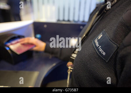 Un agent de la Force frontalière vérifie les passeports des passagers à l'arrivée dans le terminal 2 du terminal Queen de l'aéroport de Heathrow, qui a ouvert pour la première fois au public. Banque D'Images