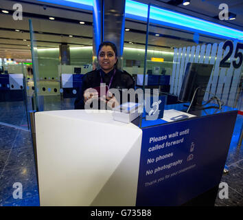 Un agent de la Force frontalière vérifie les passeports des passagers à l'arrivée dans le terminal 2 du terminal Queen de l'aéroport de Heathrow, qui a ouvert pour la première fois au public. Banque D'Images