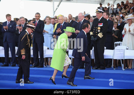 La reine Elizabeth II et le duc d'Édimbourg marchent avec le président François Hollande de France alors qu'ils arrivent pour une cérémonie internationale avec les chefs d'État à Sword Beach en Normandie pour marquer le 70e anniversaire du débarquement du débarquement. Banque D'Images