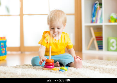 Bambin enfant jouant avec des jouets colorés. Enfant jouant avec des jouets en bois à la maternelle ou garderie. Dans les jardins d'enfant. Banque D'Images