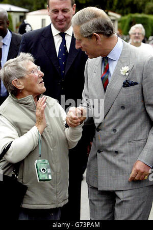 Gladys Elles, 85 ans, de Bristol, prend le Prince de Galles à la main lorsqu'il marche dans le village de Trefriw, dans la vallée de Conwy, au nord du pays de Galles, au cours d'une visite pour voir comment la région s'était rétablie après de fortes inondations en février. Banque D'Images