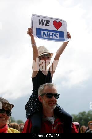 Une jeune fille est titulaire d'un cœur nous signe dans le NHS la foule lors de la NHS Greenwich et Lewisham La chorale sur La pyramide la scène du festival de Glastonbury, à la ferme digne dans le Somerset. Banque D'Images