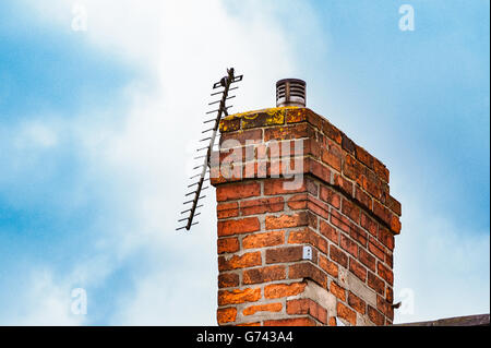 Antenne TV cassée sur une cheminée en brique against a blue sky Banque D'Images