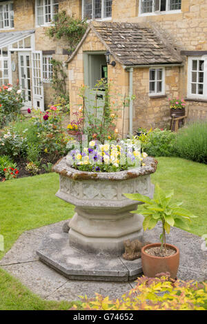 Urne en pierre pleine de fleurs en extérieur dans un cotswold cottage garden. Arles, France Banque D'Images