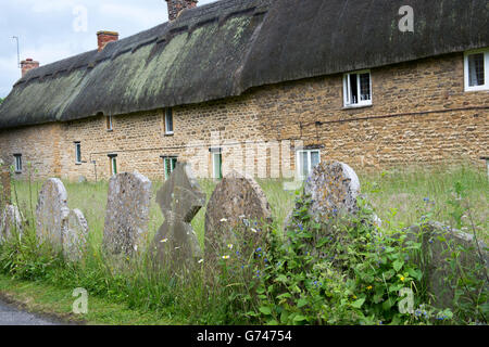 Pierres tombales en face d'une rangée de chaumières en pierre. Chipping Campden, Cotswolds, Gloucestershire, Angleterre Banque D'Images