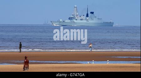 Une vue générale de la sculpture d'Antony Gormley sur la plage de Crosby alors que HMS Dauntless passe le parc d'éoliennes juste à côté de la plage de Crosby, Merseyside, le bateau fait partie du festival de la rivière Mersey qui a lieu ce week-end à Liverpool. Banque D'Images