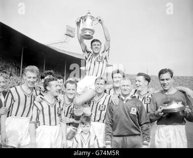 Johnny Dixon, capitaine de l'Aston Villa, est président de la FA Cup, après avoir reçu le trophée de la Reine au stade Empire, Wembley. Au premier plan se trouve la mascotte du club. Villa avait battu Manchester United par deux buts à un dans la finale de coupe, Banque D'Images