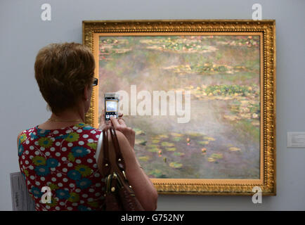 Un visiteur prend une photo sur son téléphone d'une œuvre de Claude Monet, Nympheas (Water Lilies), 1906, qui est estimée à 20-30 millions de livres sterling, lors d'une séance photo pour Sotheby's 250 millions de livres sterling Impressionist & Modern Art and Contemporary Art Summer Sales à New Bond Street, Londres. Banque D'Images