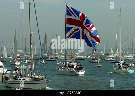 Un yacht vole un énorme jack d'Union alors qu'il sort de la médina sur l'île de Wight, où les conditions bénignes et le soleil élevé ne signifiait que peu de vent, retardant le début de la course le premier jour de la semaine des cowes de Skandia,la plus ancienne et la plus grande régate de voile au monde. Banque D'Images