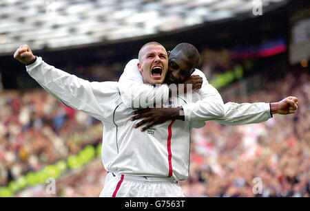 Le capitaine de l'Angleterre David Beckham (avant) célèbre avec son coéquipier Emile Heskey après avoir obtenu l'égaliseur d'un coup de pied gratuit contre la Grèce lors des dernières secondes du match du groupe de qualification européen neuf de la coupe du monde de la FIFA à Old Trafford, Manchester. Banque D'Images