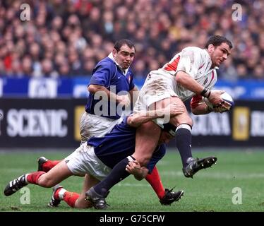 Le capitaine d'Angleterre Martin Johnson (à droite) est pris par Oliver Magne et Raphael Ibanez (à gauche) du pack français lors de leur match des six Nations de la Lloyds TSB au Stade de France à Paris. Banque D'Images