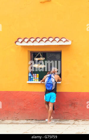 Jeune homme afro-antillaise d'acheter des rafraîchissements dans un magasin ou un bar et bavardant à Trinidad, Cuba Banque D'Images