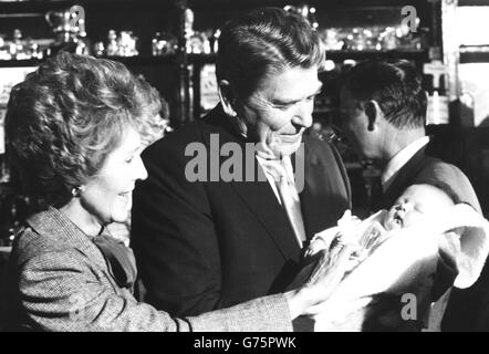 Le président Ronald Reagan et son épouse Nancy tiennent un bébé de trois semaines lors d'une visite au pub O'Farrell dans le village de Ballyporeen. Banque D'Images