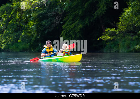 Famille sur les kayaks et canoës tour. Le père et l'enfant dans la pagaie kayak dans une rivière sur une journée ensoleillée. En été, les enfants du camp de sport. Banque D'Images