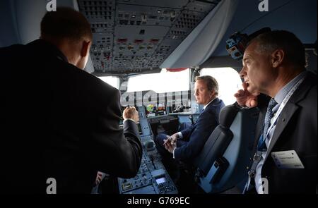 Le Premier ministre David Cameron est assis dans le siège des co-pilotes dans le poste de pilotage lorsqu'il est présenté autour d'un Airbus A350 lors d'une visite au salon de l'aéronautique de Farnborough en 2014 dans le Hampshire. Banque D'Images