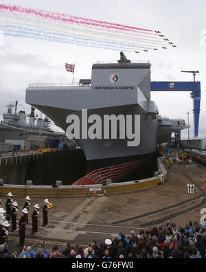 Les flèches rouges survolent alors que la reine Elizabeth II nomme officiellement le nouveau porte-avions de la Royal Navy, le HMS Queen Elizabeth, lors d'une visite au chantier naval de Rosyth en Écosse. Banque D'Images