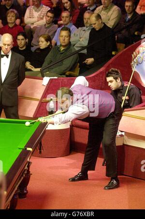 Stephen Lee d'Angleterre joue un tir regardé par son adversaire et champion défenseur, Ronnie O'Sullivan d'Angleterre (à droite) et arbitre John Williams (à gauche) pendant le quart de finale du match des Championnats du monde de snooker de l'ambassade au Crucible, Sheffield. Banque D'Images