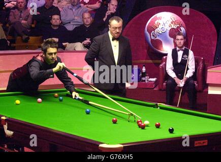 Le Ronnie O'Sullivan d'Angleterre joue un tir observé par l'arbitre Eirian Williams (au centre) et par Stephen Hendry d'Écosse lors des demi-finales des Championnats du monde de snooker de l'ambassade au Crucible, Sheffield. Banque D'Images