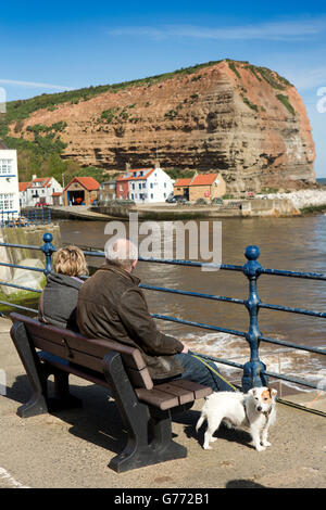 Royaume-uni, Angleterre, dans le Yorkshire, Staithes, les visiteurs assis dans sunshine le front bench Banque D'Images