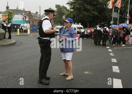 Un partisan loyaliste parle à un policier en attendant un défilé de l'ordre Orange sur Crumlin Road, à côté du quartier nationaliste Ardoyne, dans le cadre des célébrations annuelles du 12 juillet. Marquant la victoire du roi William III sur James II à la bataille de la Boyne en 1690. Banque D'Images