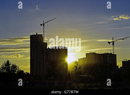 Grues de construction industrielle et de la construction au lever de soleil sur silhouettes Banque D'Images