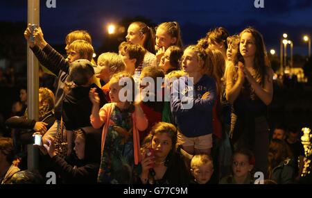 Les enfants regardent des acrobates, des pyrotechniques et des dragons géants en mouvement, avec les sons d'une partition de rock-opéra jouée par des musiciens en direct dans un spectacle appelé « Dragonus » lorsqu'ils se rendent dans les rues de Galway dans le cadre du Galway International Arts Festival. Banque D'Images