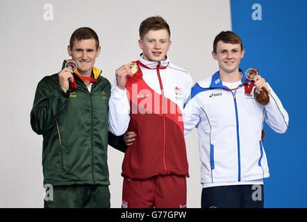 Adam Peaty (au centre), en Angleterre, remporte sa médaille d'or sur le podium pour la finale de course de 100 m des hommes, aux côtés du gagnant de la médaille d'argent Cameron van der Burgh (à gauche) en Afrique du Sud et du gagnant de la médaille de bronze Ross Murdoch (à droite) en Écosse, au Tollcross Swimming Centre, lors des Jeux du Commonwealth de 2014 à Glasgow. Banque D'Images